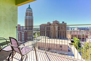 A balcony with a view of a cityscape, including a tall building and a brick building.