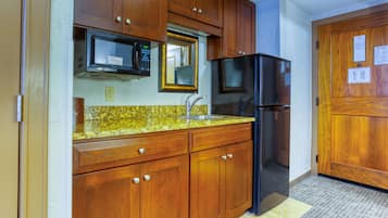 A kitchen with wooden cabinets, a microwave, a refrigerator, and a sink.
