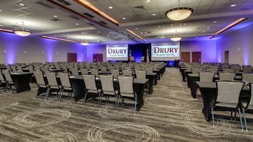 A conference room with rows of chairs, a carpeted floor, and a stage with a podium.