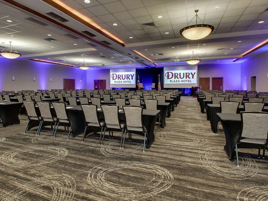 A conference room with rows of chairs, a carpeted floor, and a stage with a podium.