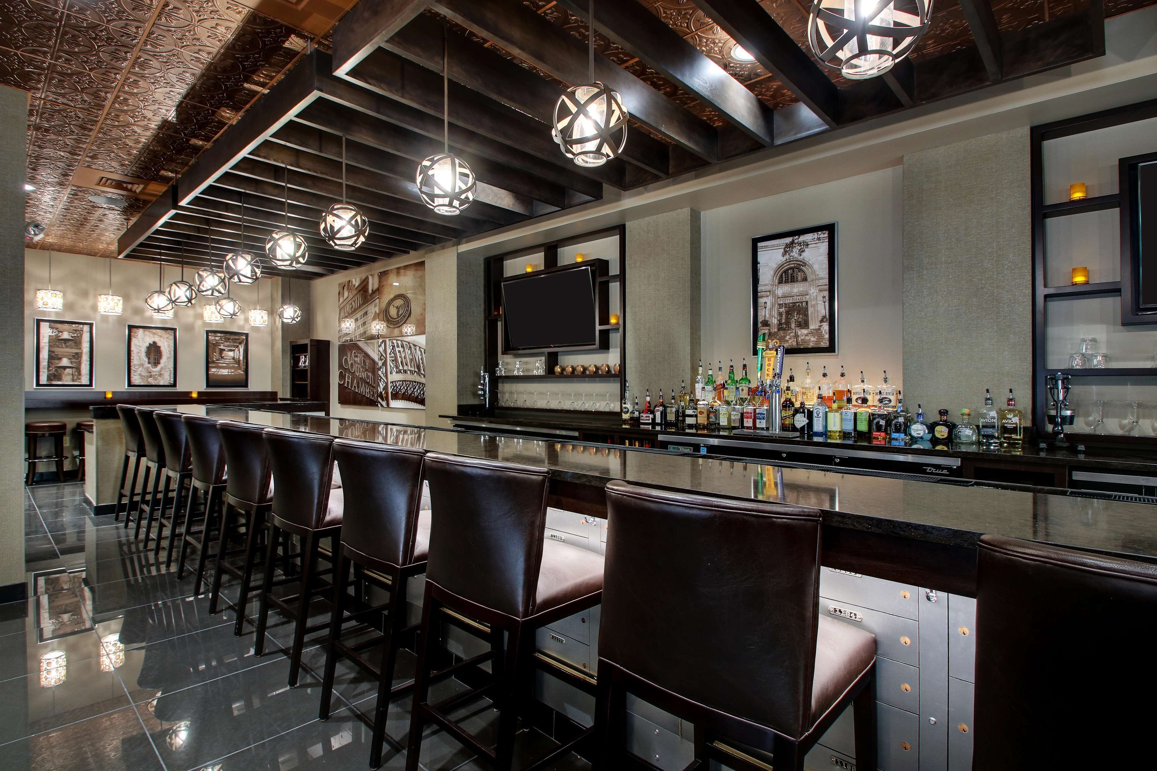 A bar area with multiple seating options, a bar counter with various bottles, and a television screen.