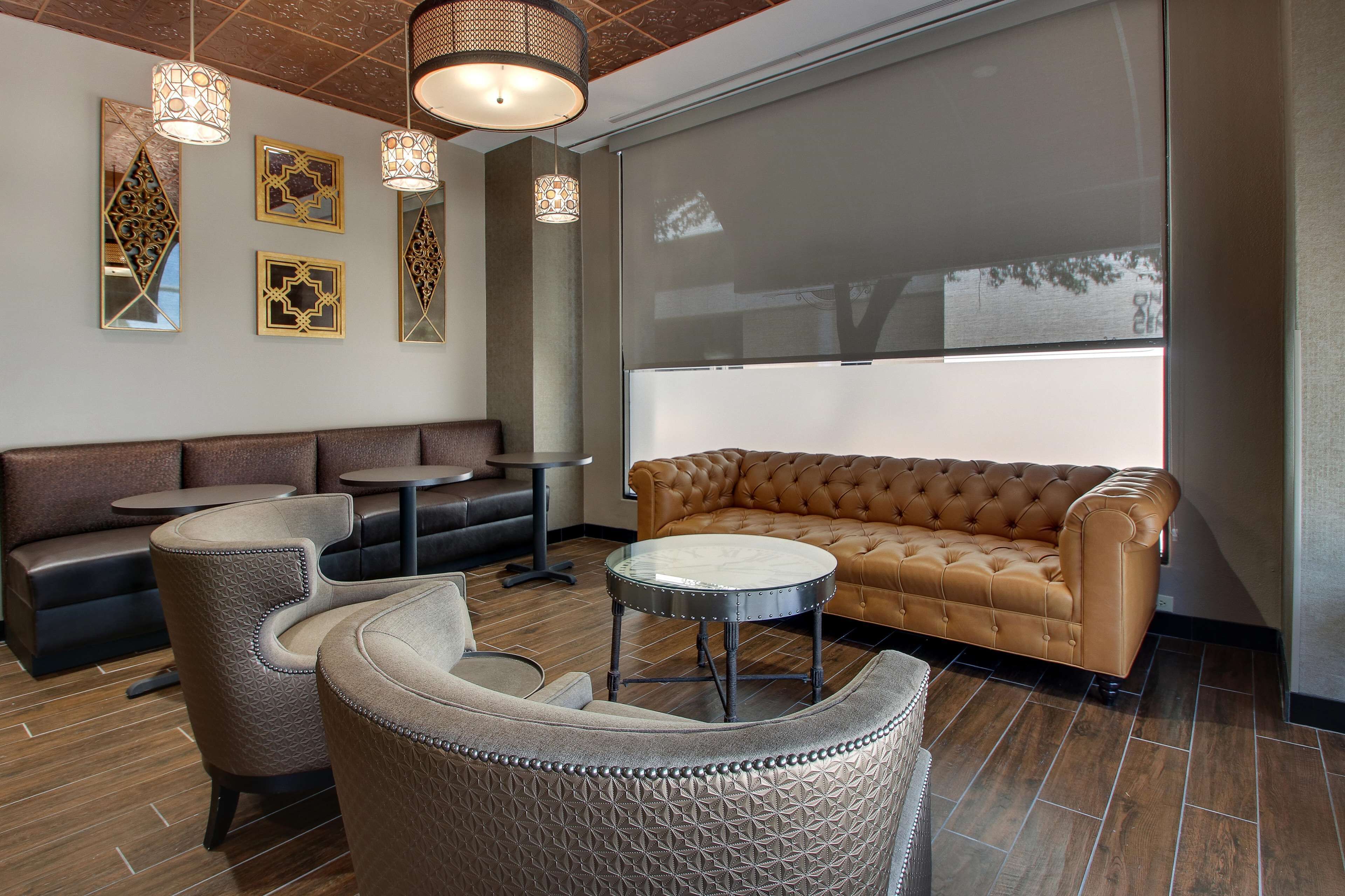 A modern lounge area with leather sofas, patterned chairs, and a round table.