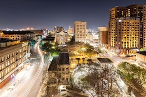 A cityscape at night with illuminated buildings, a prominent church, and a curved road.