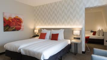 A hotel room with a large bed, two bedside tables with lamps, a red chair, and a painting on the wall.