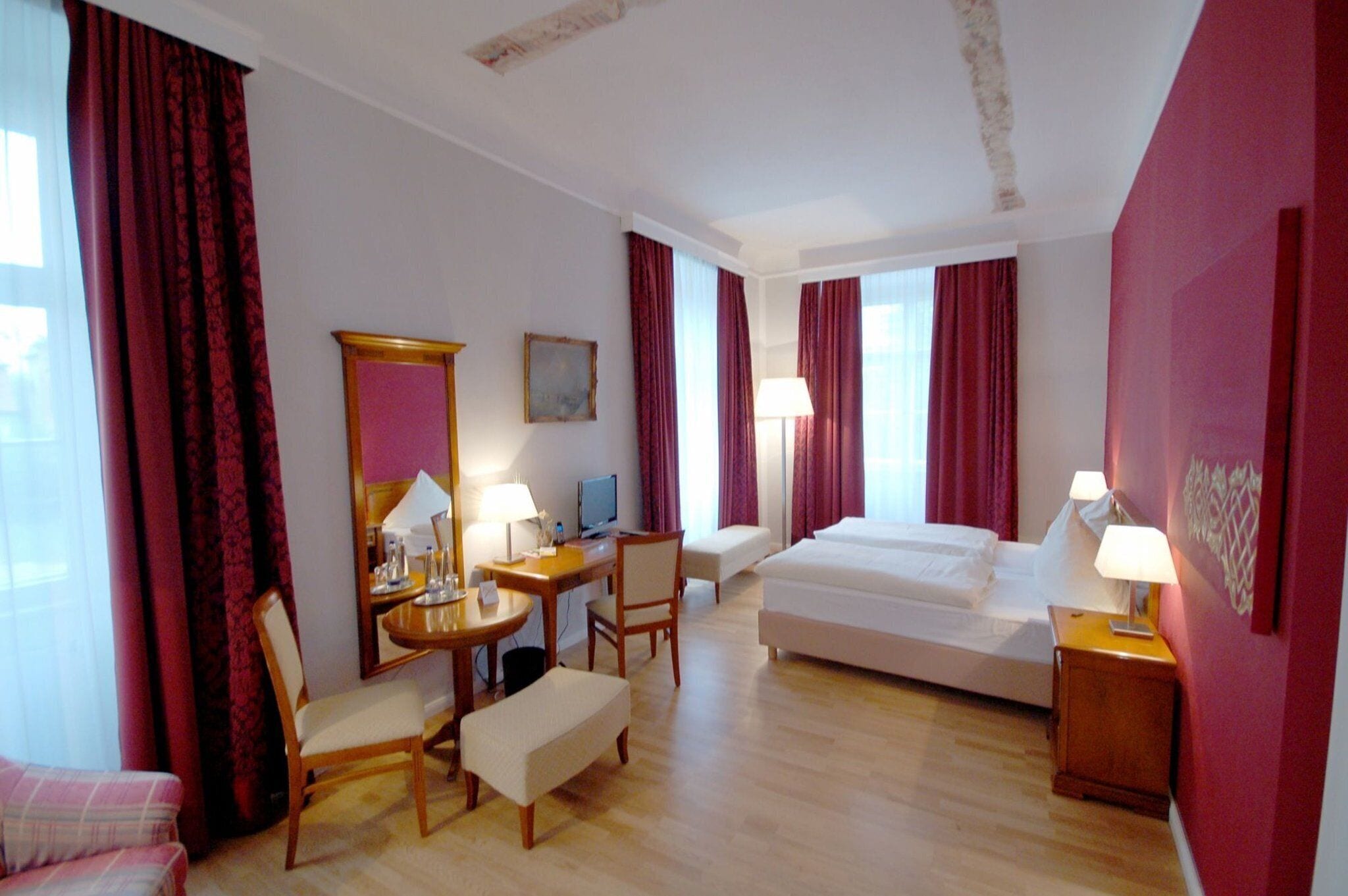 A hotel room with a bed, a desk with a computer, a chair, a small table, and a sofa.