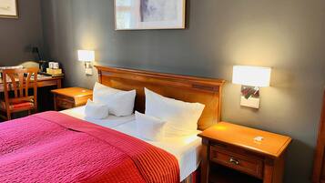 A hotel room with a large bed, two bedside tables, a desk, and a chair.
