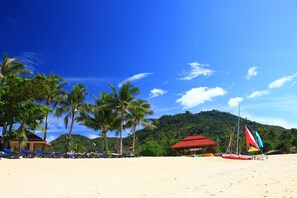 Praia particular, areia branca, espreguiçadeiras, guarda-sóis 