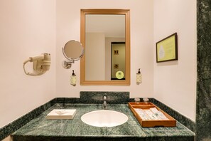 Un bany amb un lavabo de marbre, un mirall, un assecador d'eixugat i un certificat emmarcat a la paret.