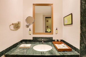 Un baño con un lavabo de mármol, un espejo, un secador de pelo y un certificado enmarcado en la pared.