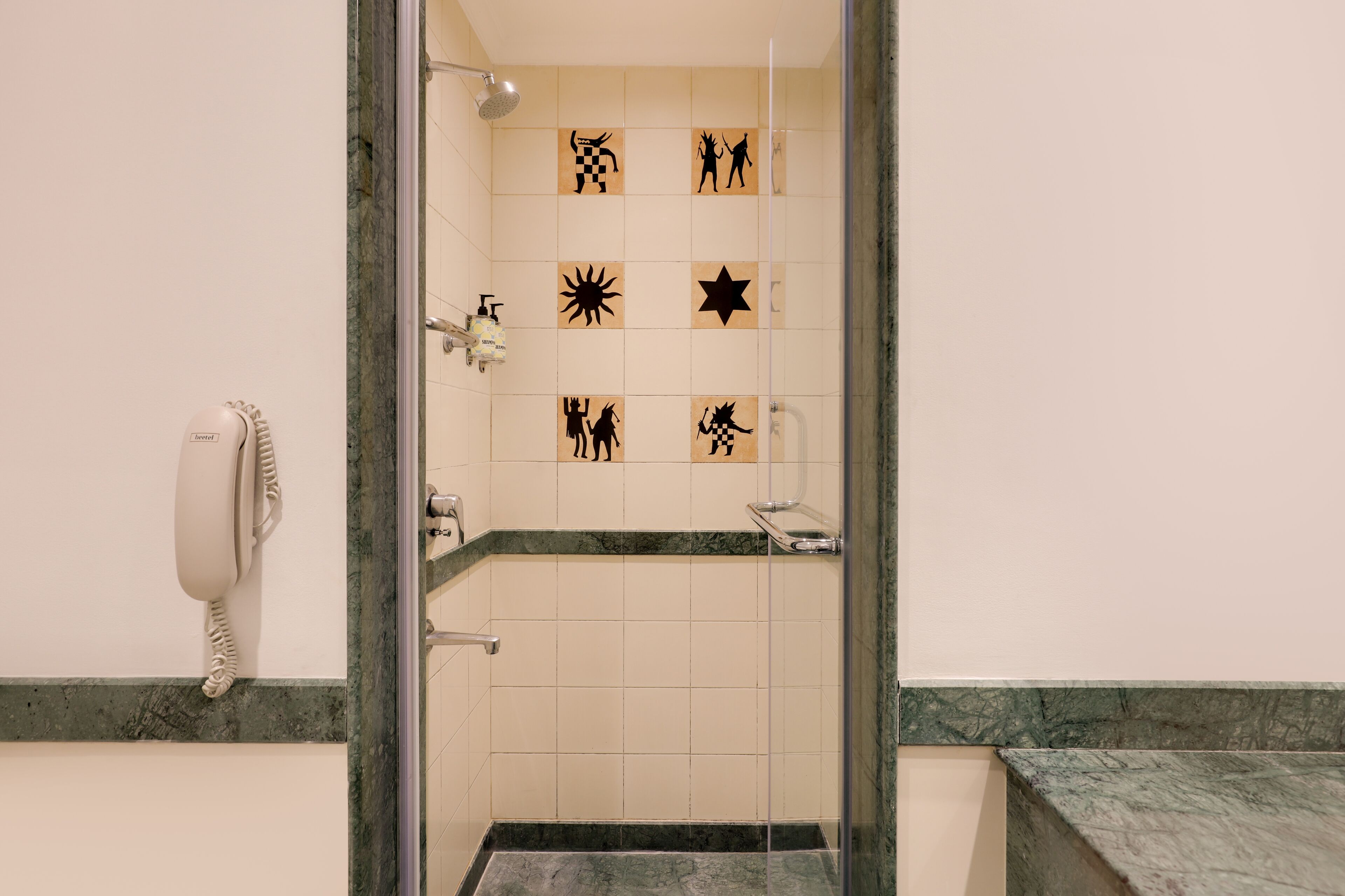 A bathroom with a shower, a hand dryer, and a tiled wall with various symbols.