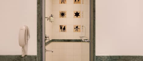 Un baño con ducha, secamanos y pared de azulejos con varios símbolos.