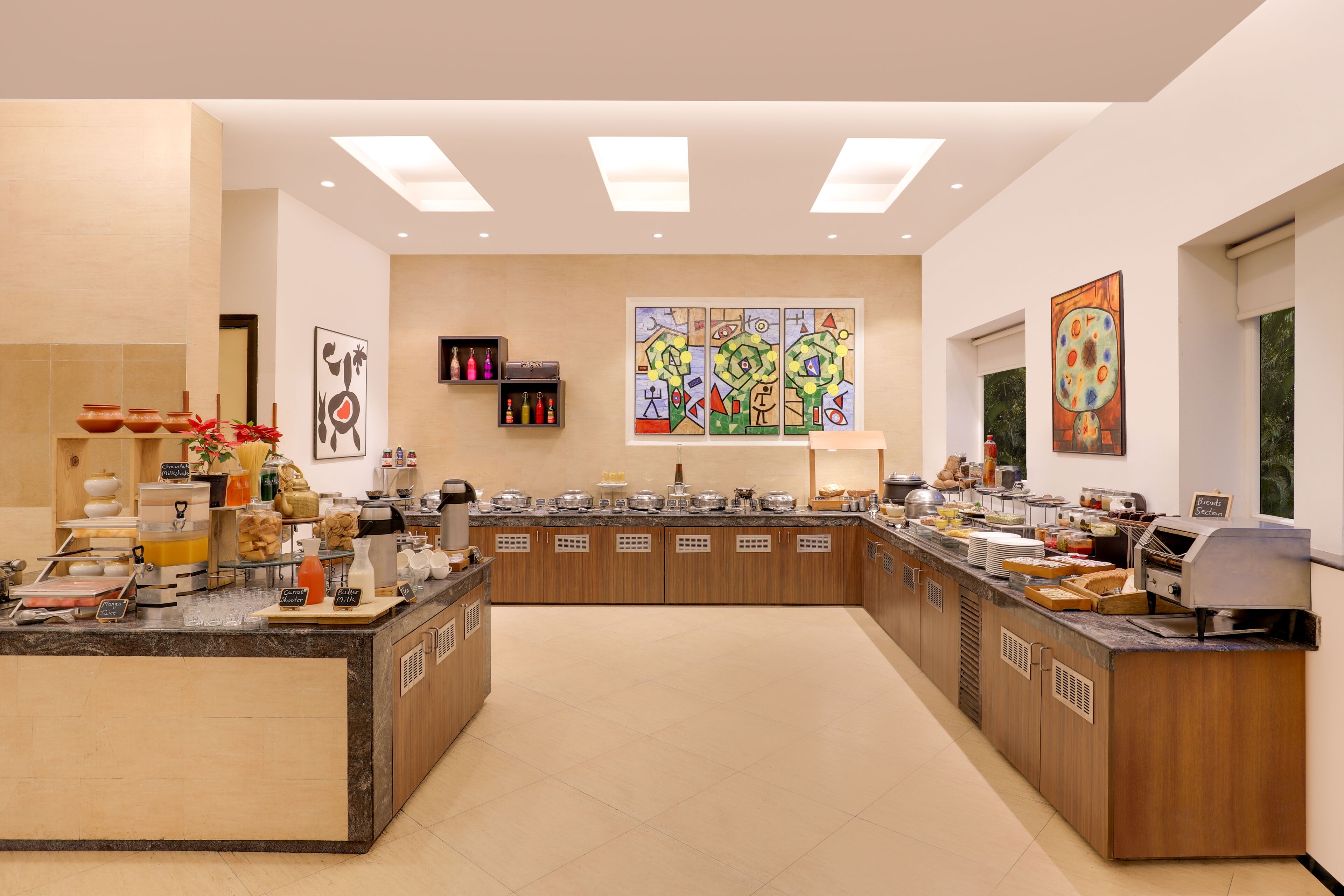 A spacious buffet area with multiple food stations, a large window with artwork, and a clean, modern design.