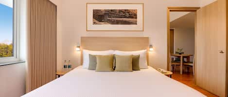 A neatly made bed with a headboard, a bedside table with a lamp, and a framed picture on the wall.