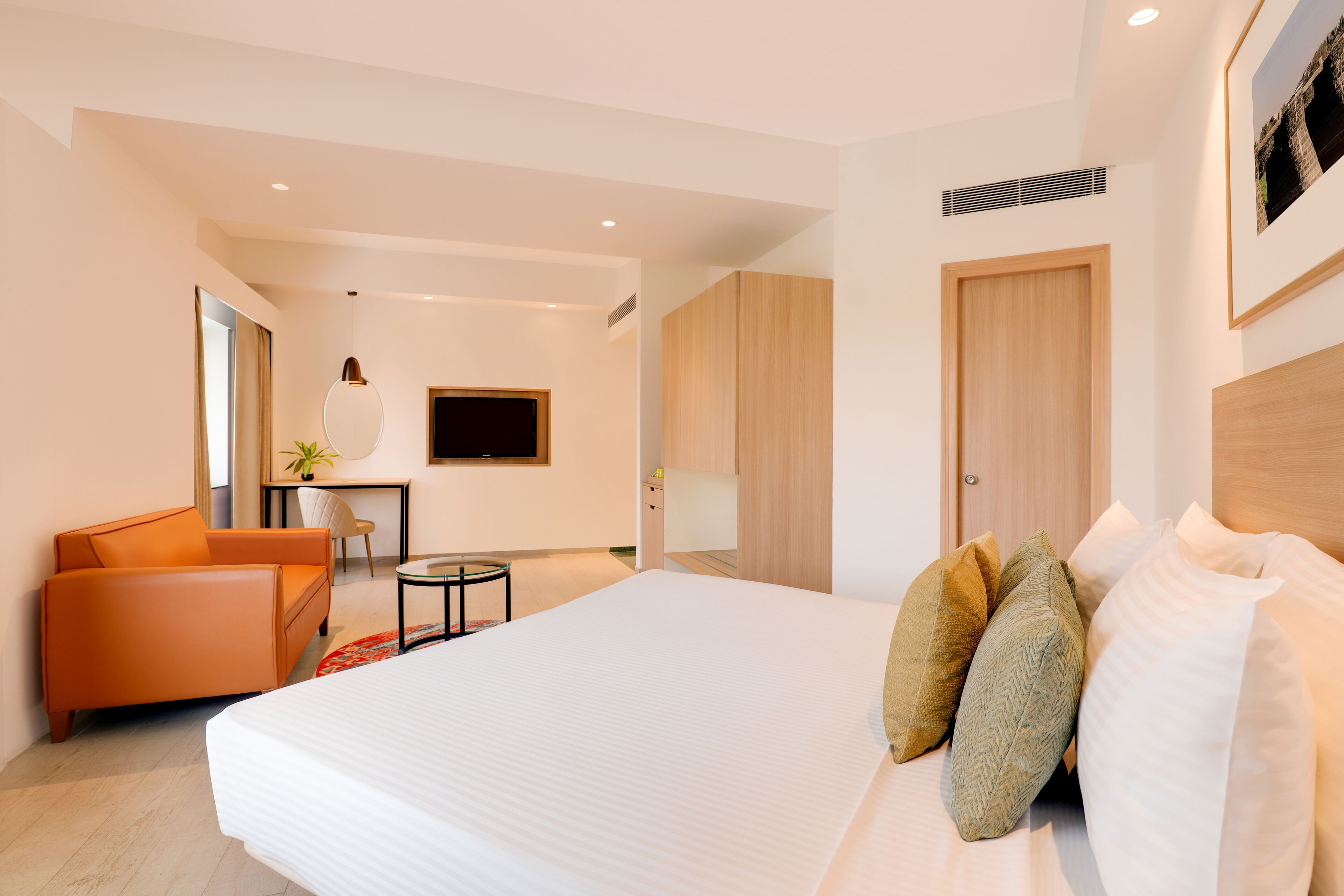 A modern hotel room with a large bed, a desk, a chair, and a TV.