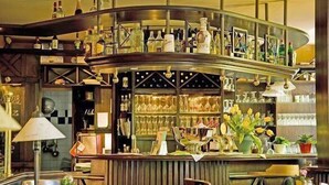 A bar area with a curved counter, shelves with bottles, and a variety of glasses. - Hotel - Restaurant Kronprinz (Falkensee)
