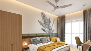 A modern bedroom with a bed, a desk, a chair, a wardrobe, and a ceiling fan. - Bawa Regency (Mumbai)
