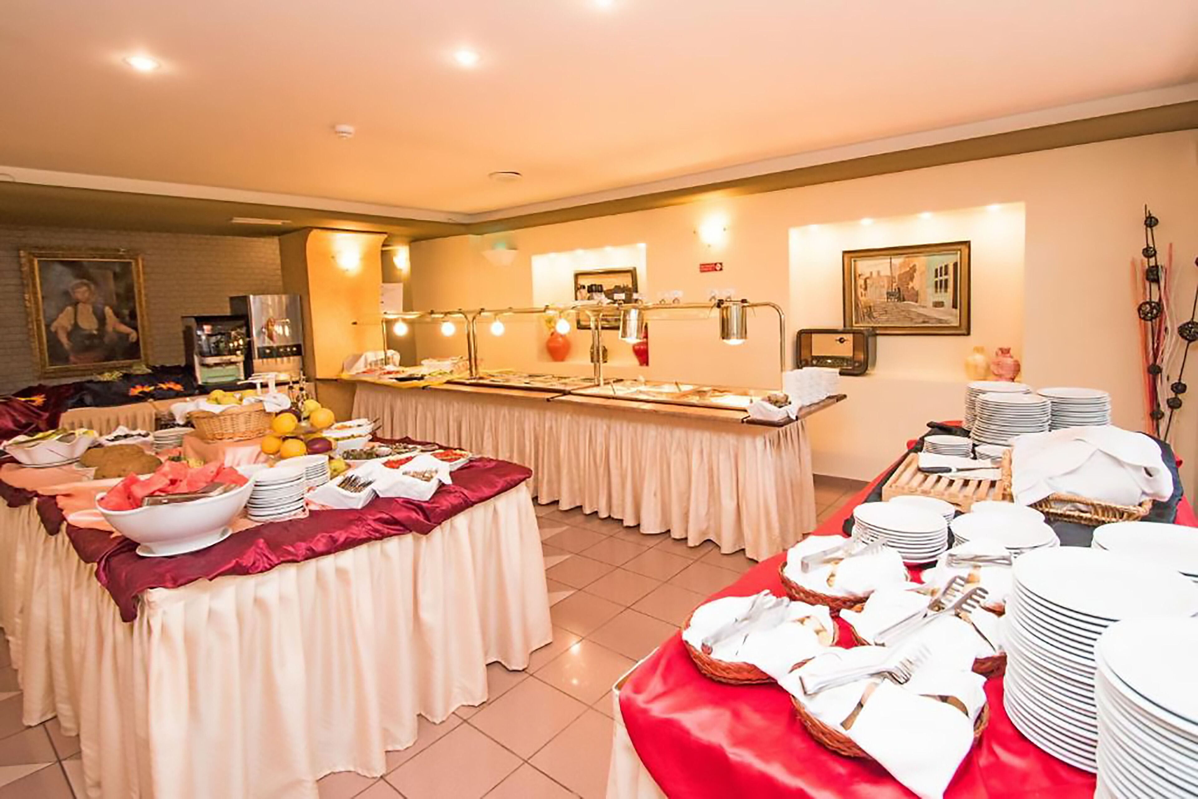 Un buffet composé de plusieurs tables recouvertes de nappes, où sont présentés divers plats et couverts.