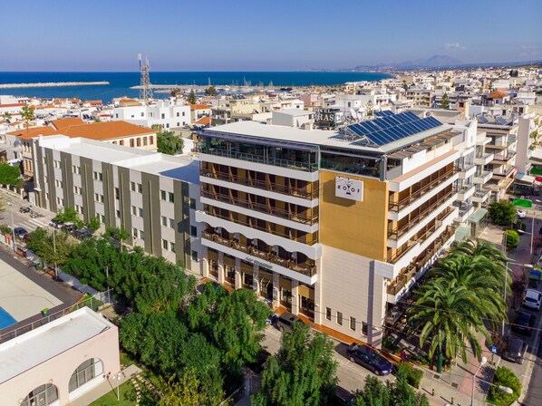A multi-story hotel with balconies, a rooftop terrace with solar panels, and a view of the sea. - Brascos (Rethymno)