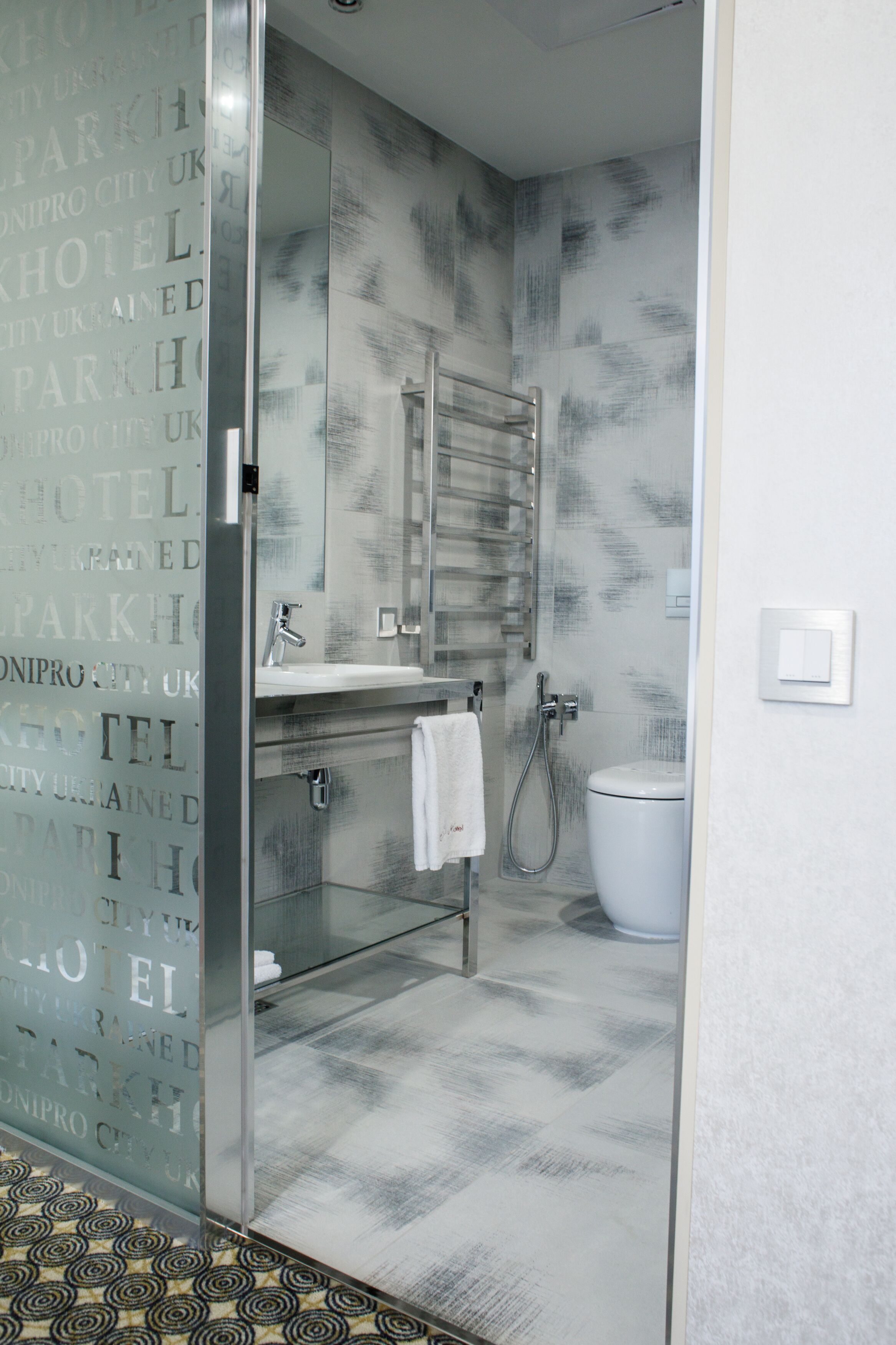 A modern bathroom with a glass shower enclosure, a white sink, and a toilet.
