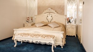 A classic four-poster bed with a floral bedspread, a matching bench, and a nightstand with a vase of flowers. - Park Hotel (Dnipro)