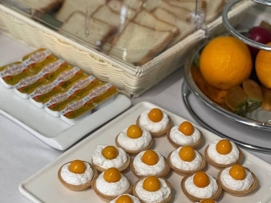 A buffet table with various food items including sandwiches, mini quiches, and a fruit bowl.