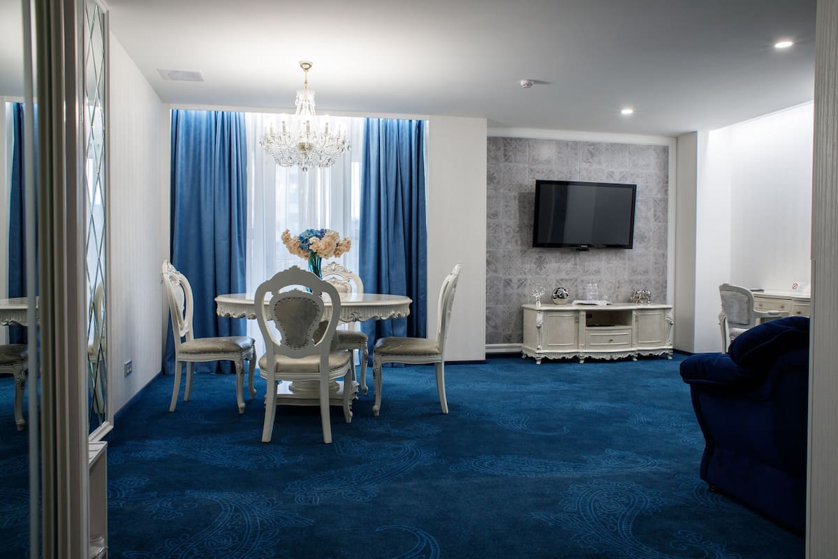 Ein Hotelzimmer mit Essbereich, einem an der Wand montierten Fernseher und einem blauen Teppich.