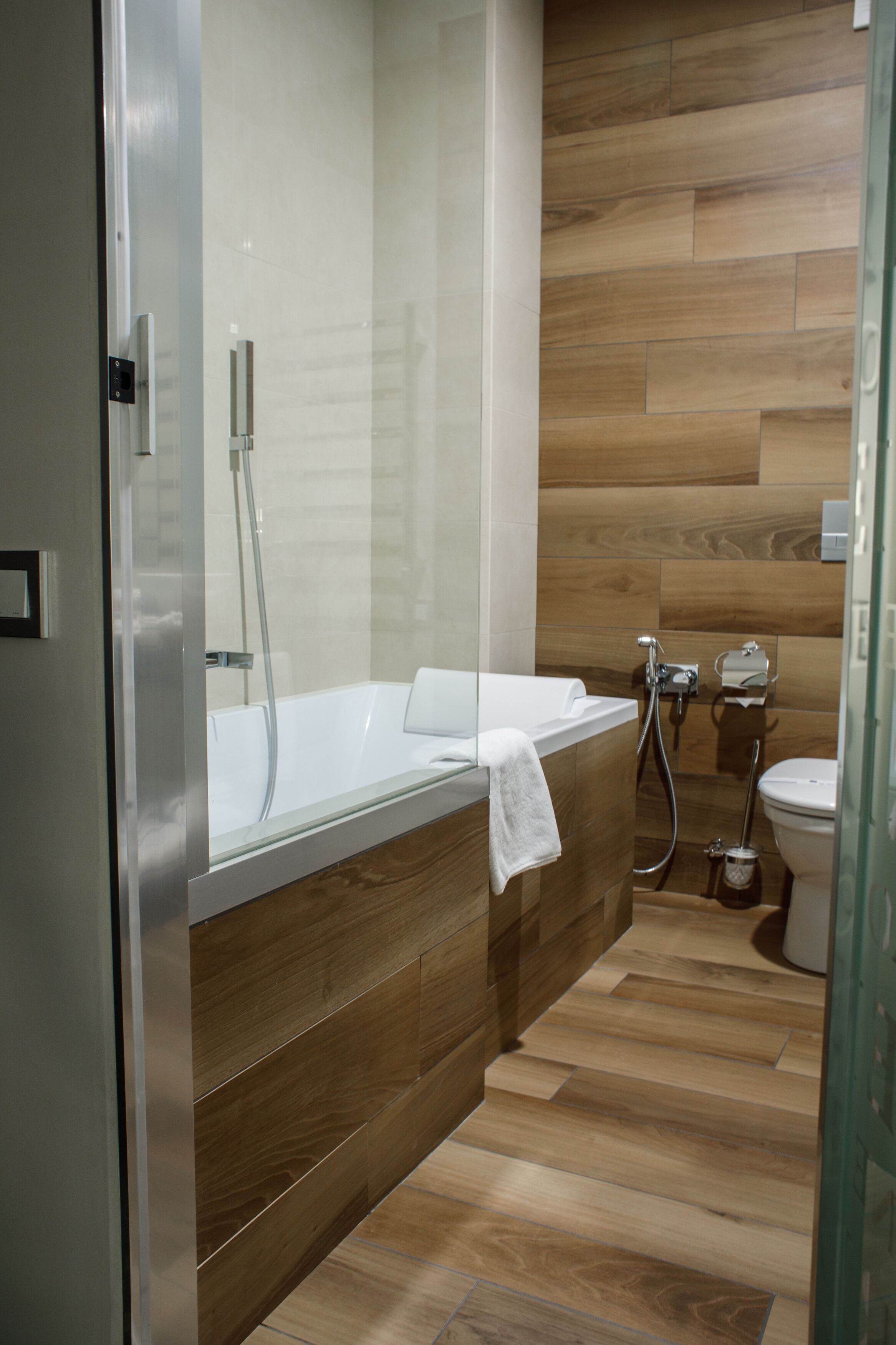 Un baño moderno con cabina de ducha de vidrio, tocador de madera y un inodoro.
