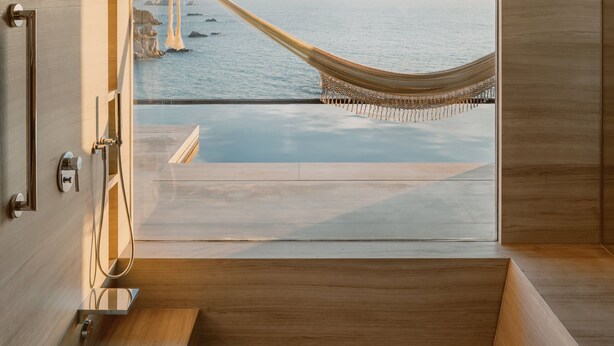 Un baño moderno con un ventanal grande, piso de madera y una bañera.