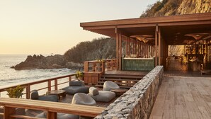 Terraza de madera con asientos, una zona de bar y vista al océano.