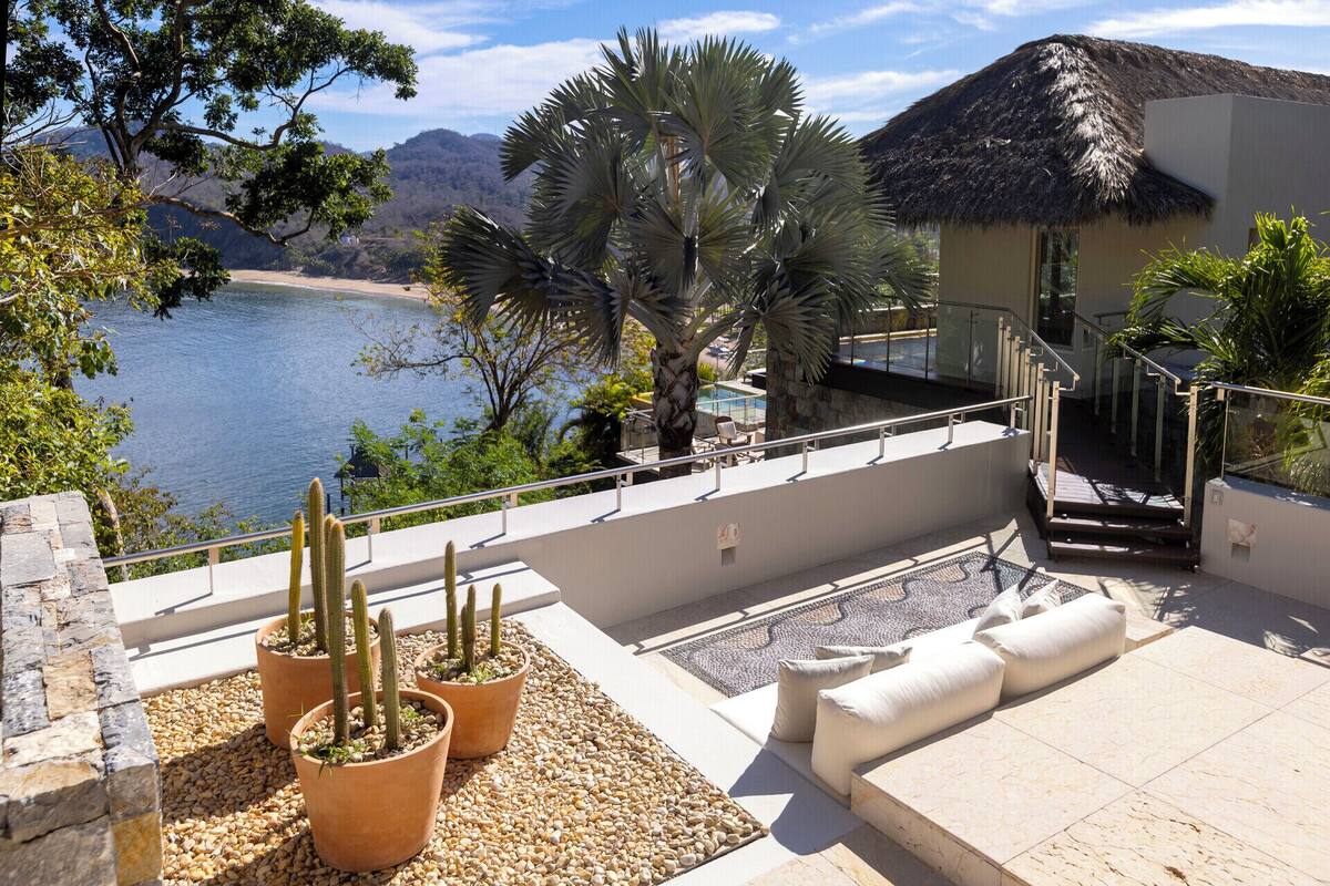 Une terrasse avec une piscine, des cactus et une vue sur la plage et les montagnes.
