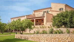 A stone building with a balcony, surrounded by a stone wall and greenery. - Finca Son Roig by Valentin (Porreres)