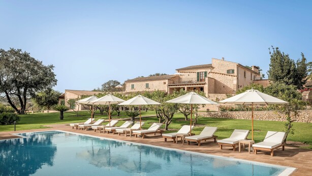A pool with lounge chairs and umbrellas, a stone building in the background, and a well-maintained lawn. - Finca Son Roig by Valentin (Porreres)