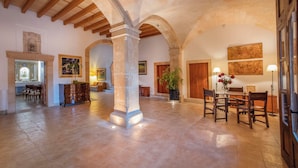 A spacious interior with high ceilings, stone arches, and a dining area with wooden furniture. - Finca Son Roig by Valentin (Porreres)