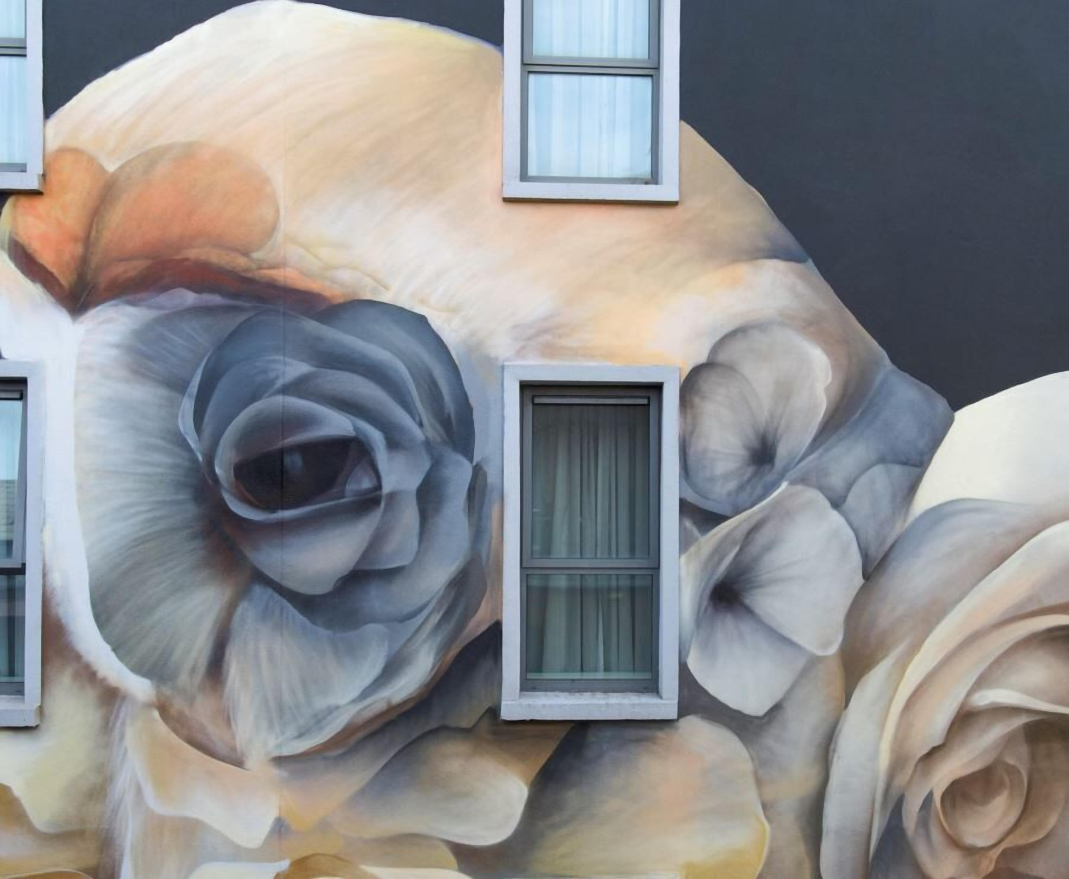 Fachada de edificio con grandes murales florales y ventanas rectangulares.
