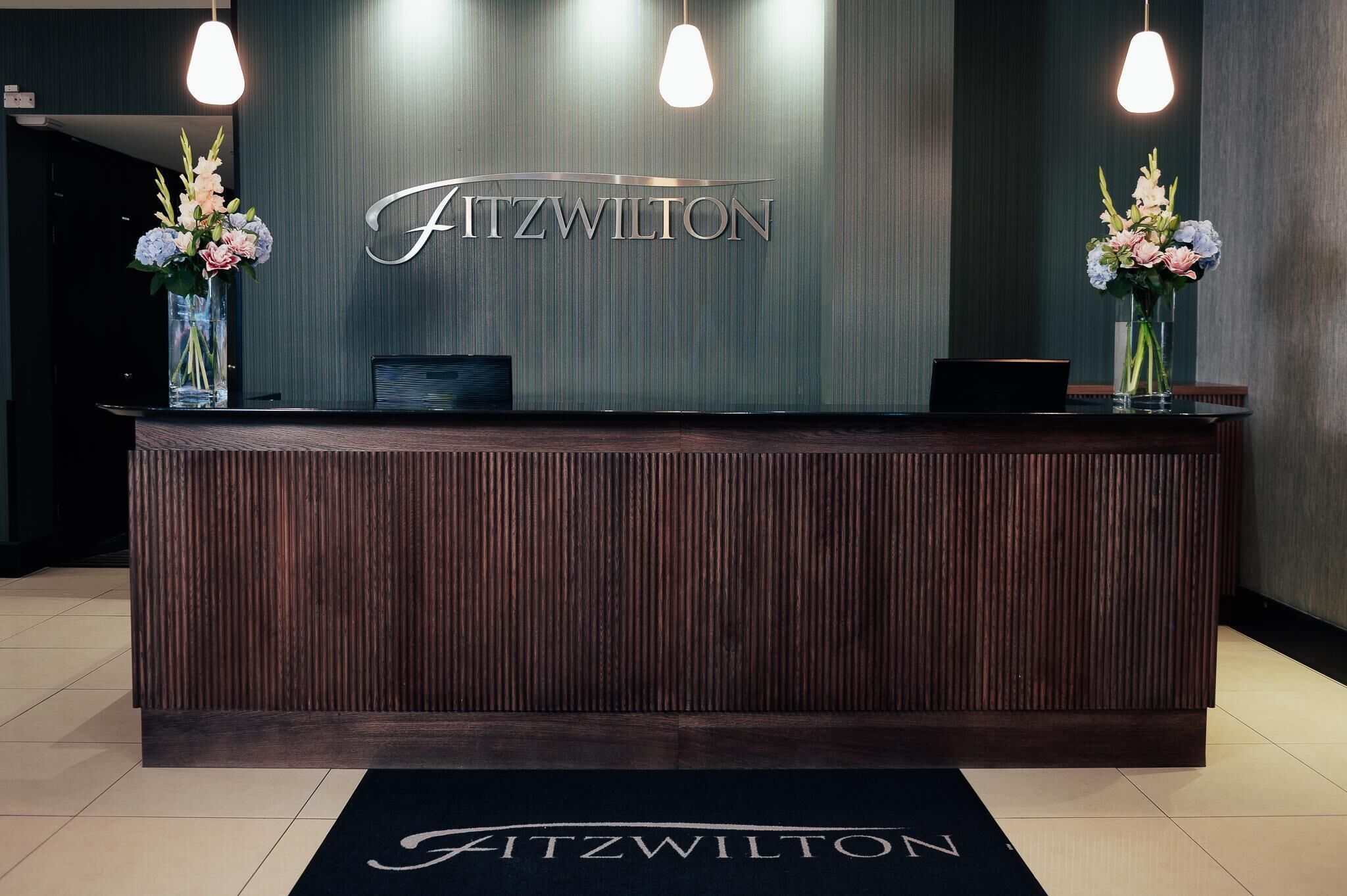 Un mostrador de recepción con el nombre 'Fitzwilton' al fondo.