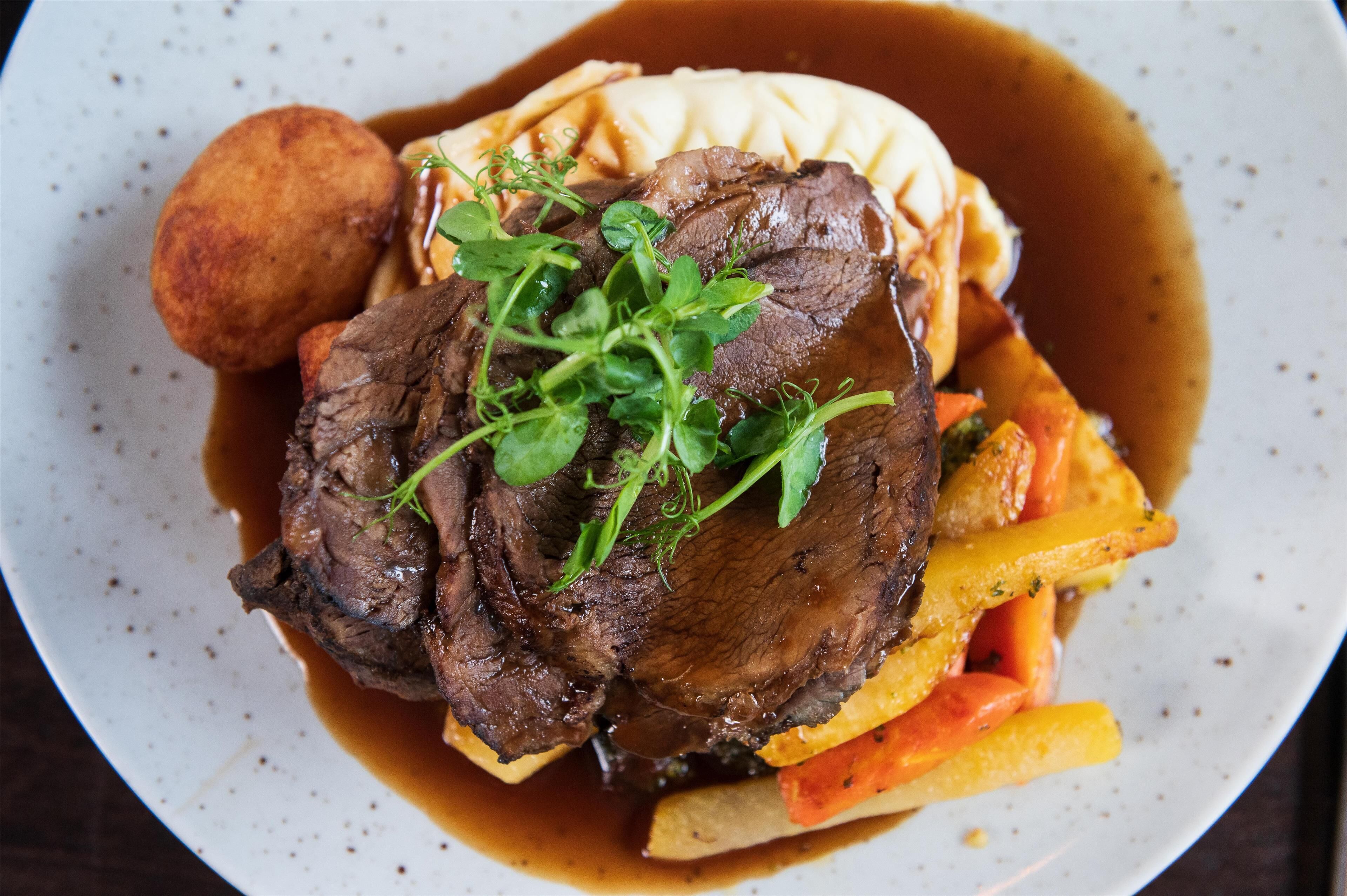 A plate of food with beef, mashed potatoes, and vegetables.