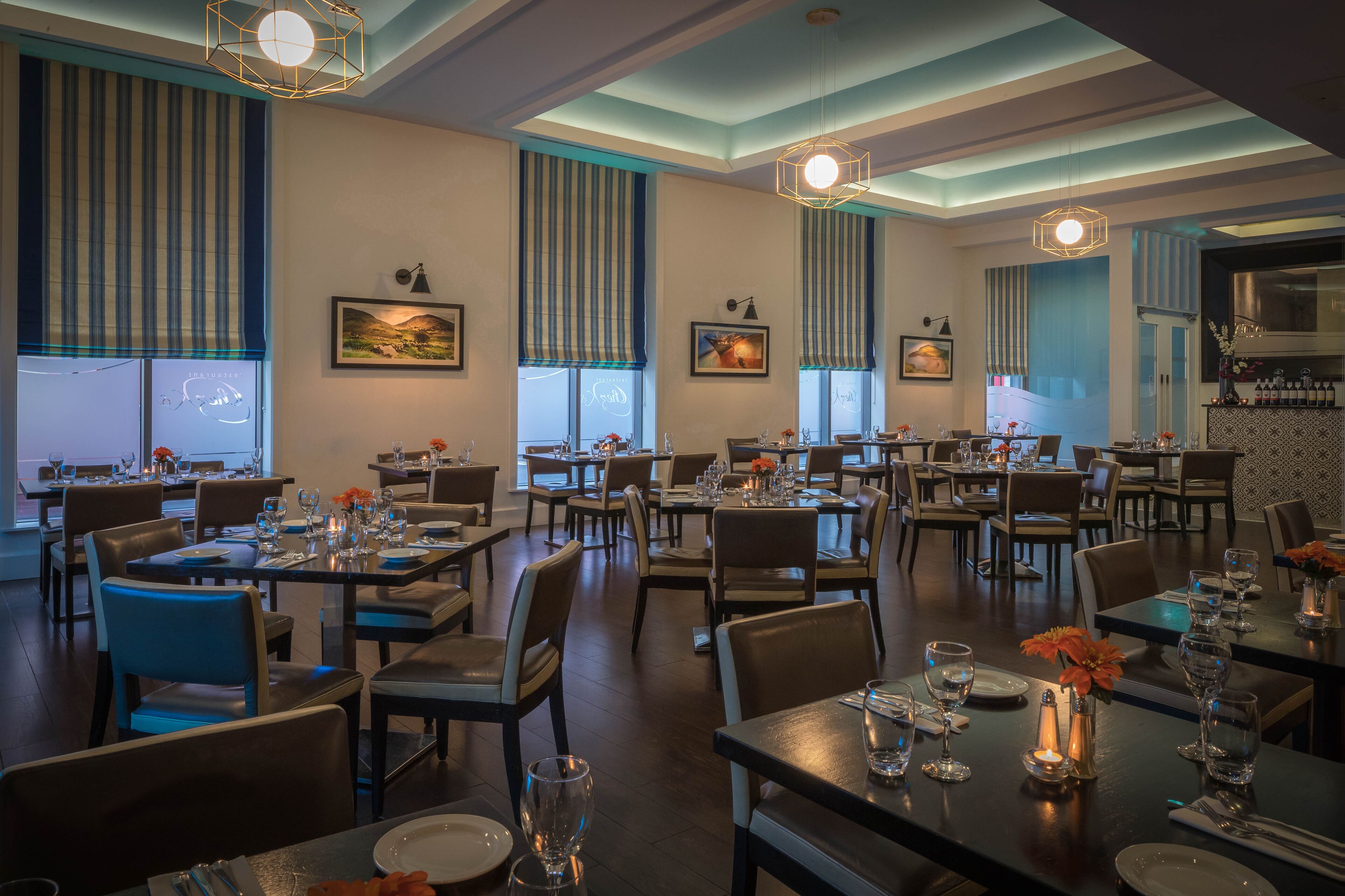 A restaurant with multiple dining tables, chairs, and hanging light fixtures.