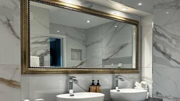 Une salle de bain moderne avec deux lavabos, un grand miroir et des murs en marbre.