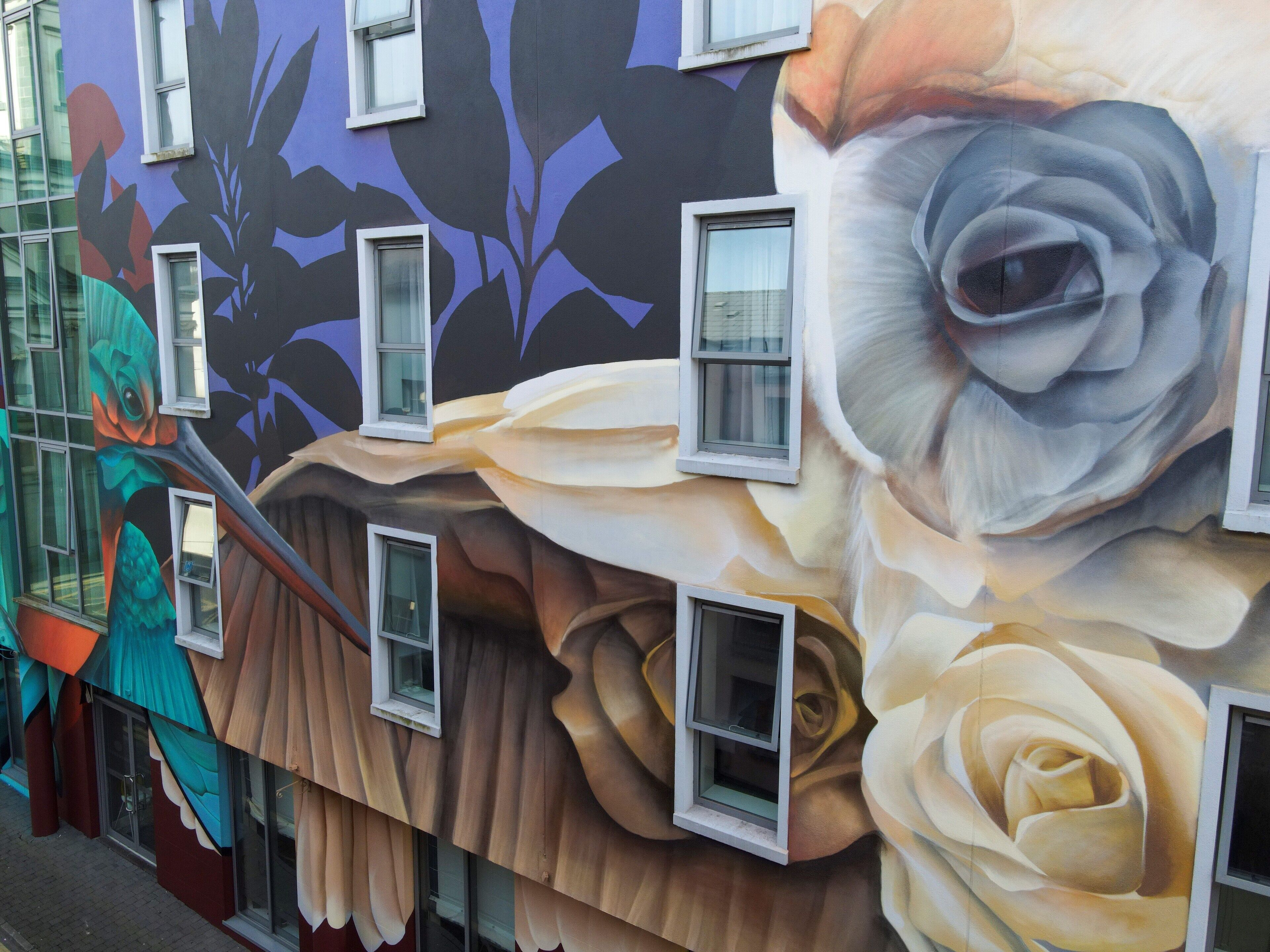 A building facade with large windows and a mural of a rose.