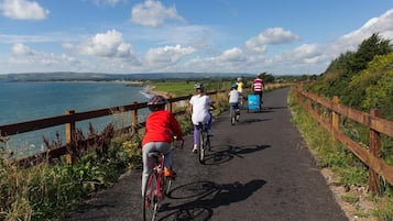 A paved path with cyclists, a wooden fence, and a view of the sea.