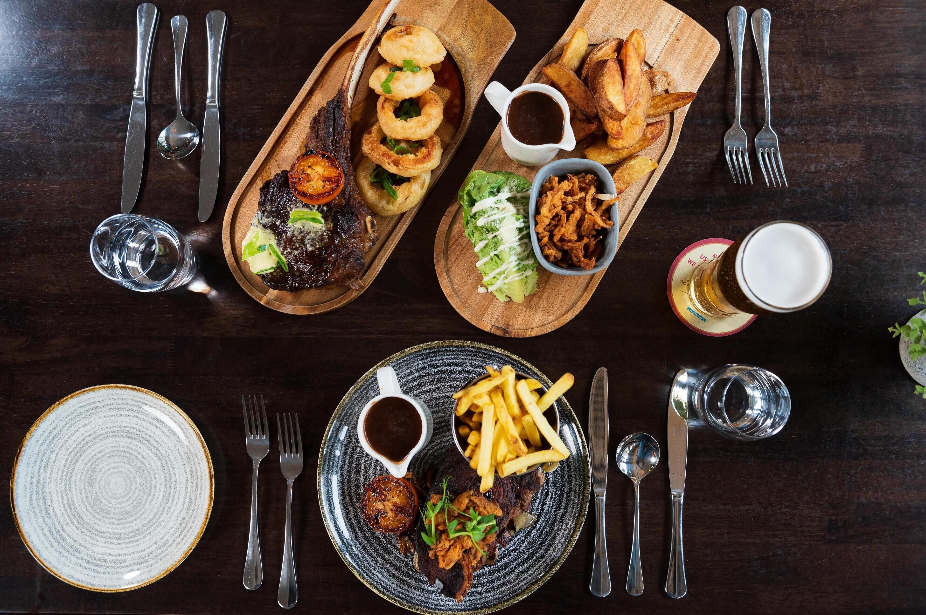 A dining table with various dishes, utensils, and glasses.
