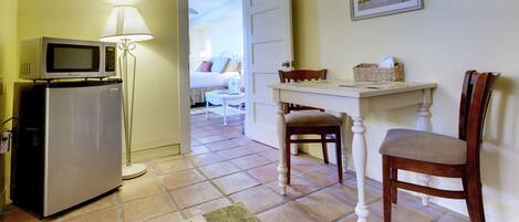 A hotel room with a kitchenette, a dining area, and a view into the bedroom.