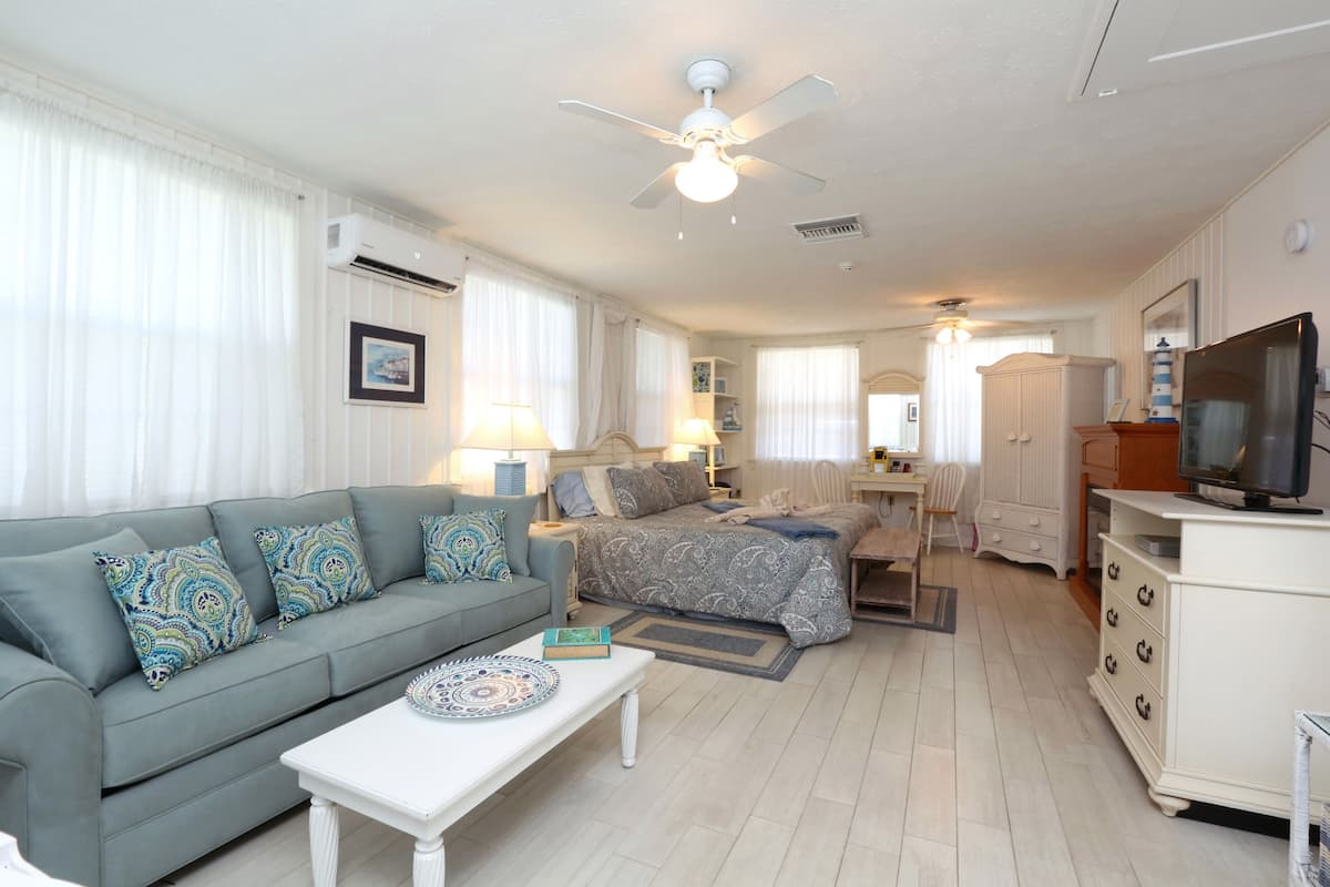 A spacious living room with a sofa, a coffee table, a TV, and a ceiling fan.