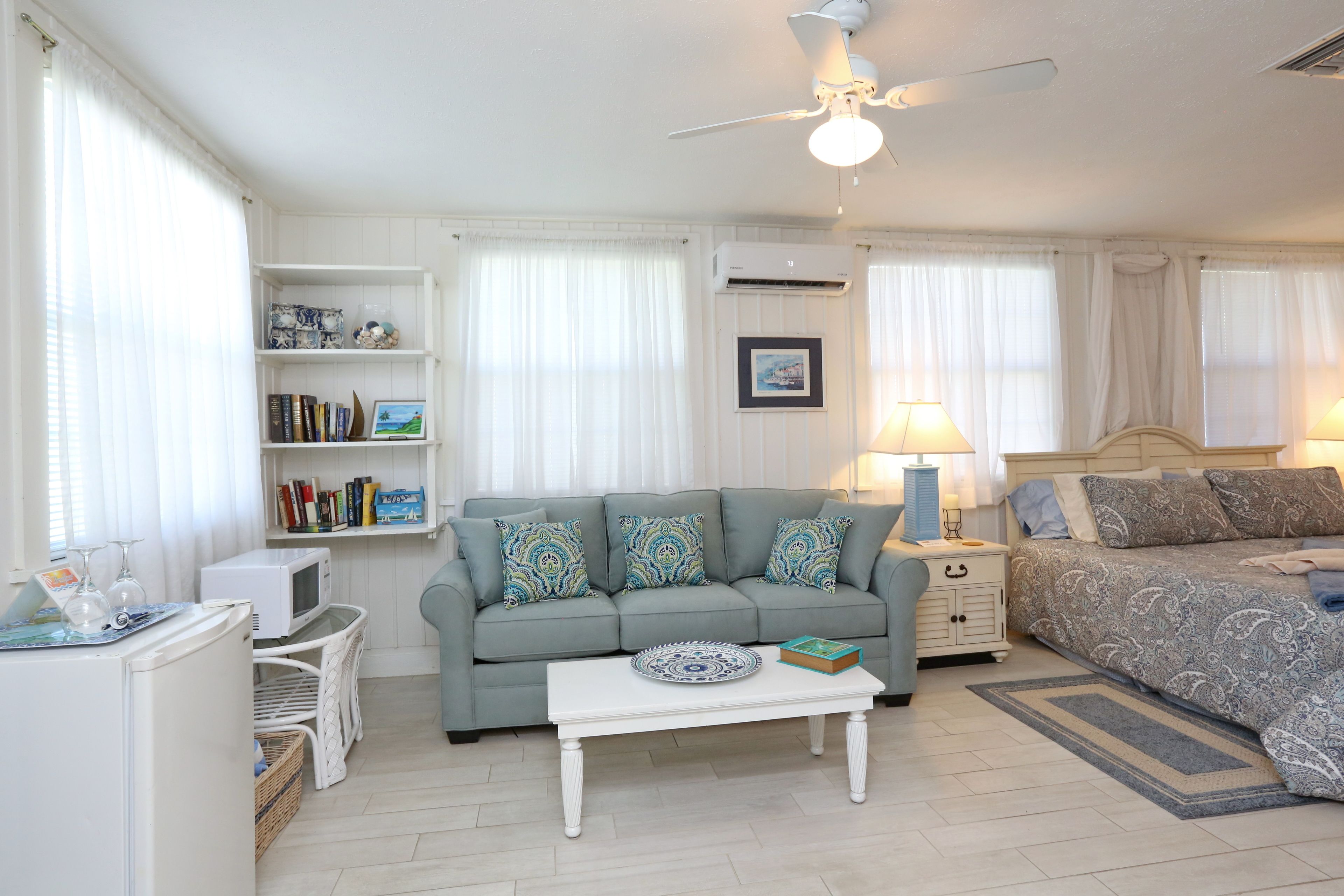 A well-lit room with a sofa, a bed, a coffee table, and a bookshelf.