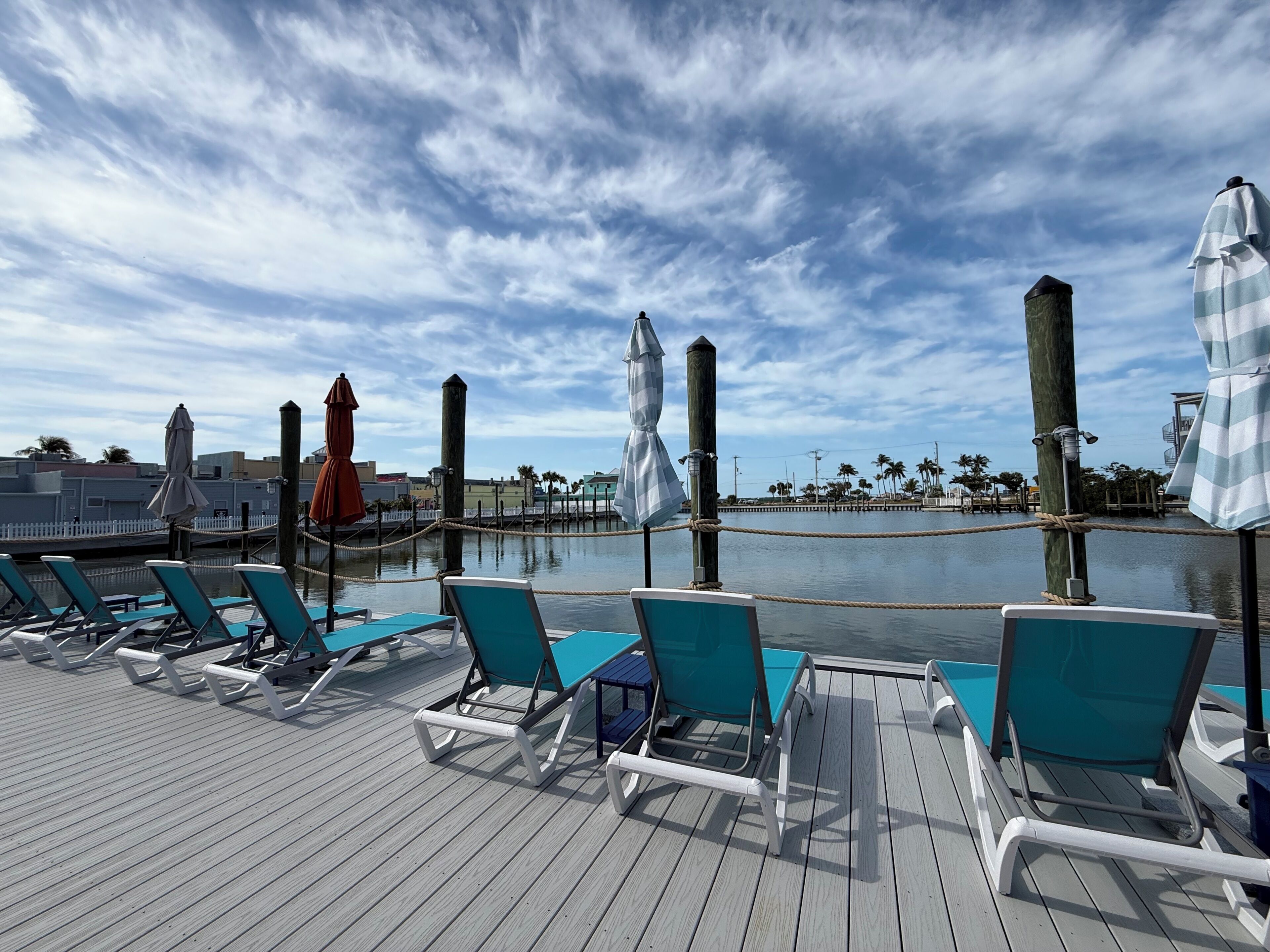 A deck with lounge chairs and umbrellas overlooking a body of water.