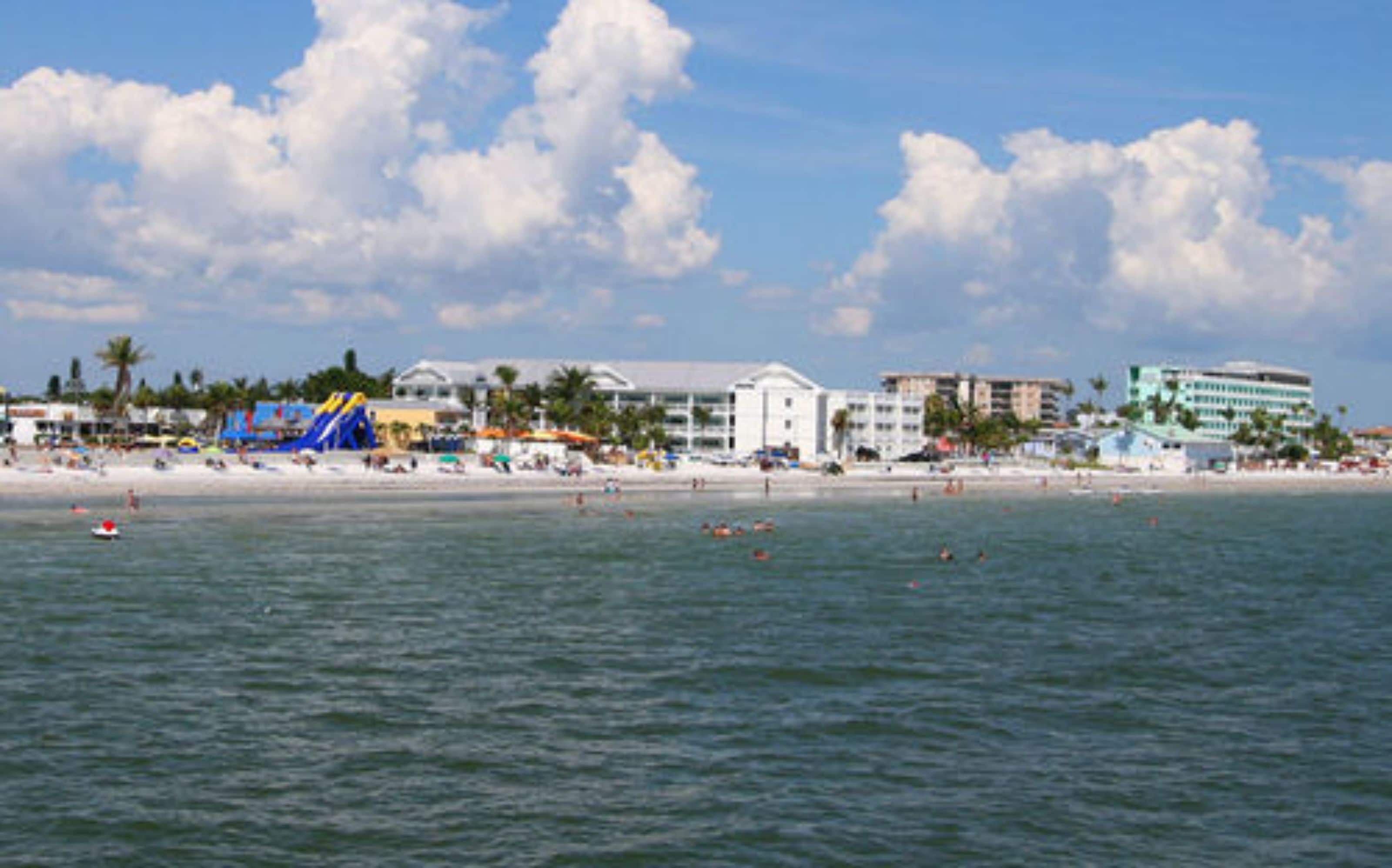 Une plage avec un parc aquatique, des bâtiments et des palmiers.