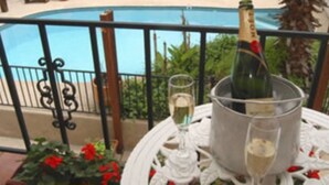 A balcony with a pool, a bottle of champagne, and a glass of champagne on a table. - The Lakehouse Bed & Breakfast (Canyon Lake)