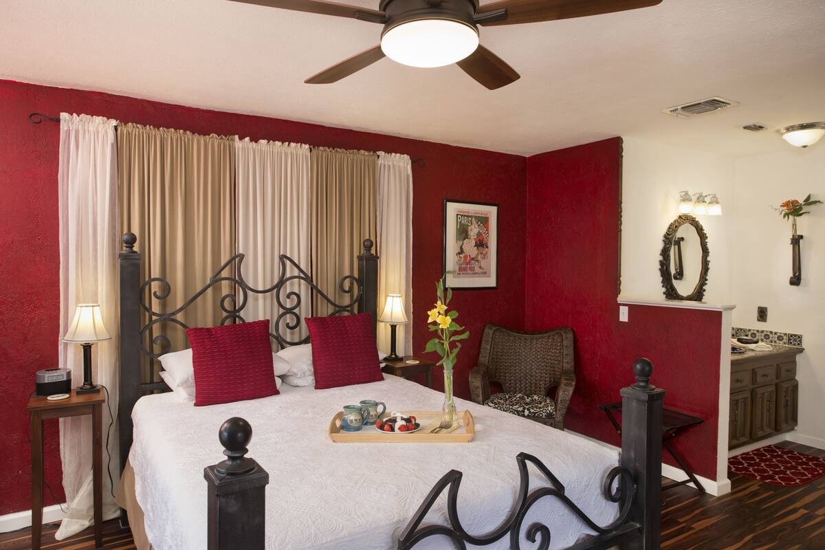 Une chambre d’hôtel comprenant un lit, une table de chevet, une chaise, un bureau et un coin salle de bain.