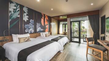 A hotel room with two beds, a desk, a chair, a balcony with a view, and a large floral mural on the wall.