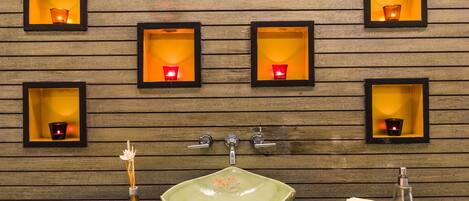 A bathroom with a green sink, multiple framed candles, and a tray of toiletries.